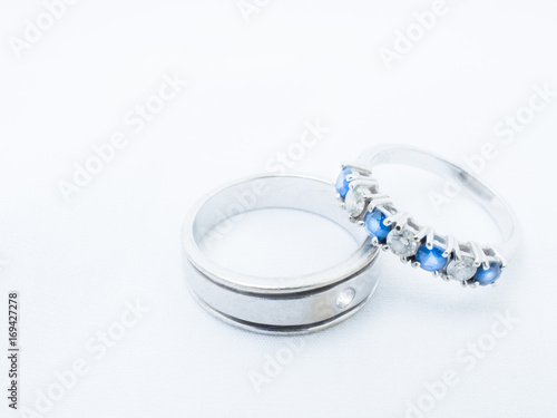 white diamond and blue gemstones on white gold wedding rings with white background and copy space