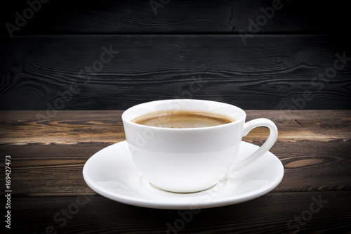  view of a freshly brewed mug of espresso coffee on rustic wooden background with woodgrain texture. Coffee break style, concept