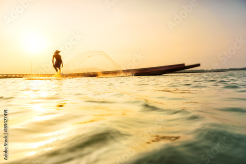 Fototapeta Naklejka Na Ścianę i Meble -  Fisherman on a fishing boat in a river at sunset,Thailand