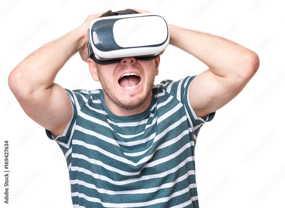 Young man with a frightened pose with virtual reality goggles watching movies or playing video games, isolated on white background. Man is looking scared. People experiencing 3D gadget technology. Young man with a frightened pose with virtual reality goggles watching movies or playing video games, isolated on white background. Man is looking scared. People experiencing 3D gadget technology.