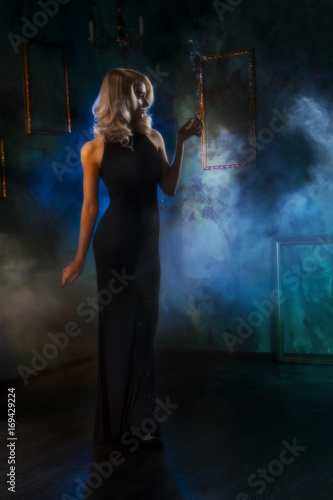 the girl with a cigarette in a theatrical fog. blurred retrostyle photo.