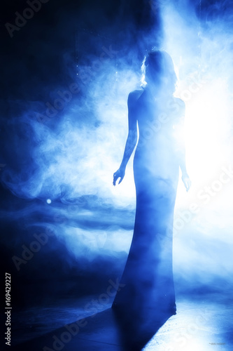 Silhouette of the beautiful girl in blue theatrical. fog.