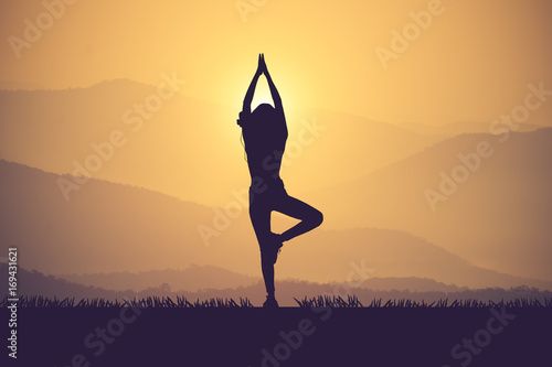 Silhouette young woman practicing yoga on the muontain at sunset.Vintage color