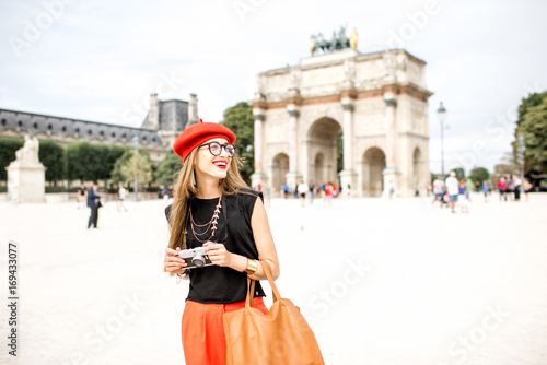 Young woman tourist in red cap standing with photo camera in front of the triumphal arch at the Tuileries park in Paris © rh2010