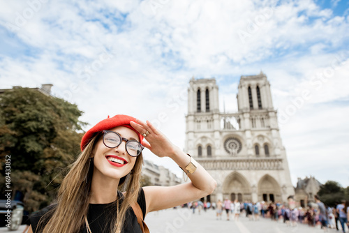 Portrait of a young woman tourist in red cap standing in front of the famous Notre Dame cathedral in Paris © rh2010