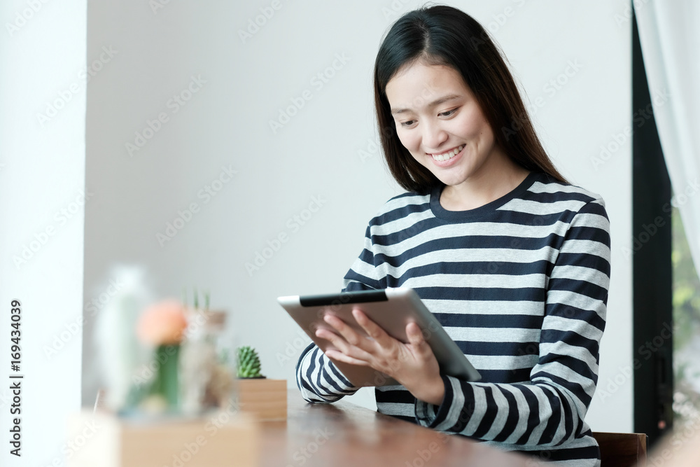 Young asian woman using tablet while sitting by window cafe background, People technology and lifestyle Young asian woman using tablet while sitting by window cafe background, People technology and lifestyle