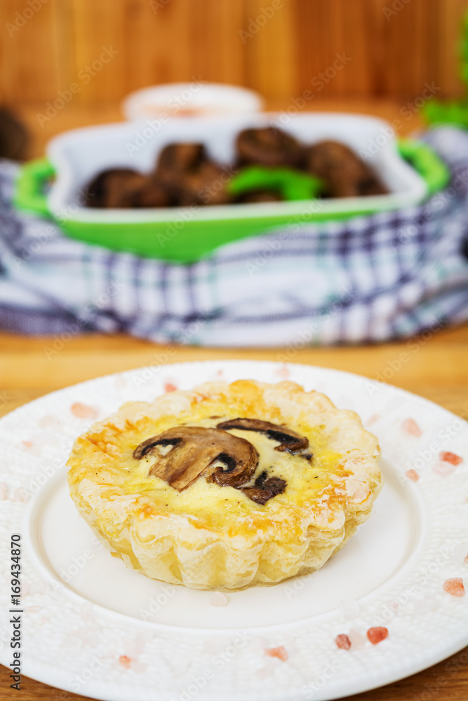 Tartlets with champignons on wooden background