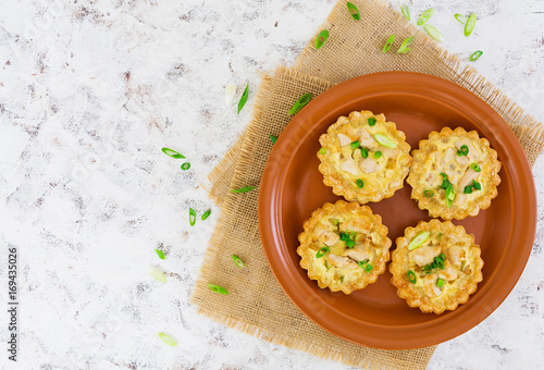 Tartlets with chicken and zucchini on white background