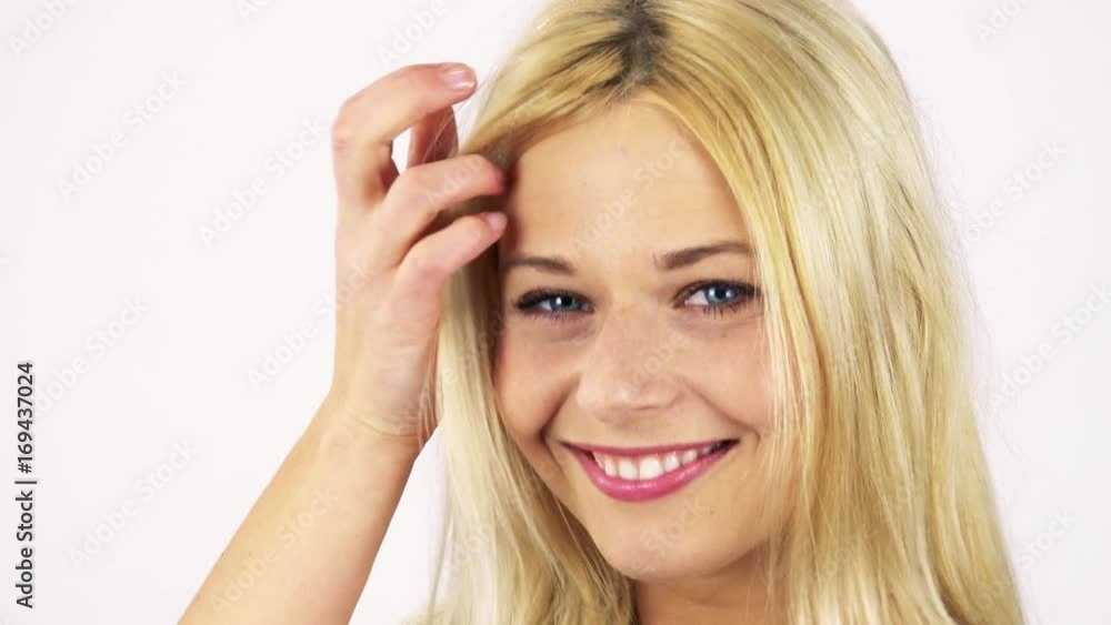 A young attractive woman turns to the camera and smiles, playing with her hair - face closeup - white screen studio A young attractive woman turns to the camera and smiles, playing with her hair - face closeup - white screen studio