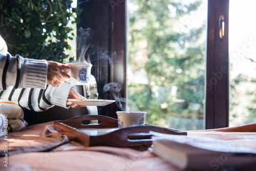 Woman drinking hot tea in bed on a winter day photo