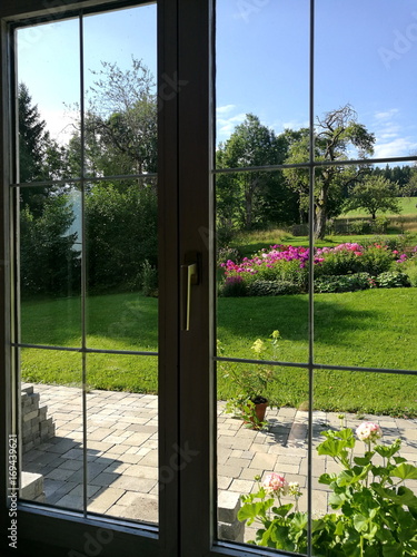 Blick aus dem Fenster eines Landhaus in den schön angelegten grünen Garten im Sommer bei Sonnenschein im Pfaffenwinkel in Rudersau bei Rottenbuch im Kreis Weilheim-Schongau im schönen Oberbayern photo