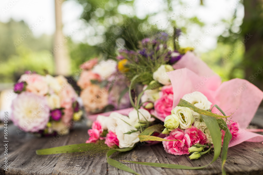 Wedding bouquet with pink, white and violet flowers - set on a wooden table. 