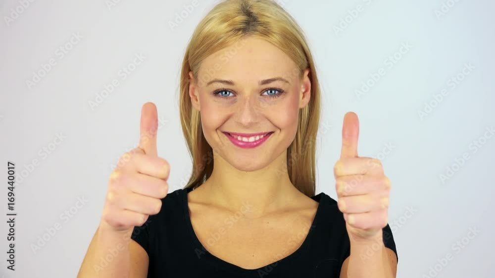 A young attractive woman shows thumbs up to the camera - closeup on the hand - white screen studio A young attractive woman shows thumbs up to the camera - closeup on the hand - white screen studio
