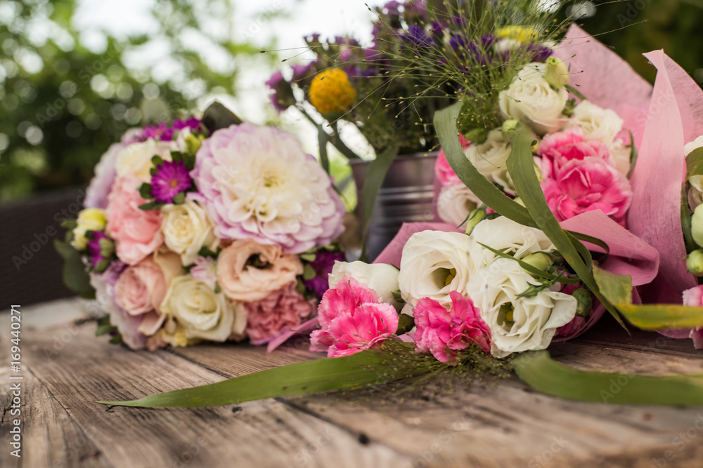 Wedding bouquet with pink, white and violet flowers - set on a wooden table. 