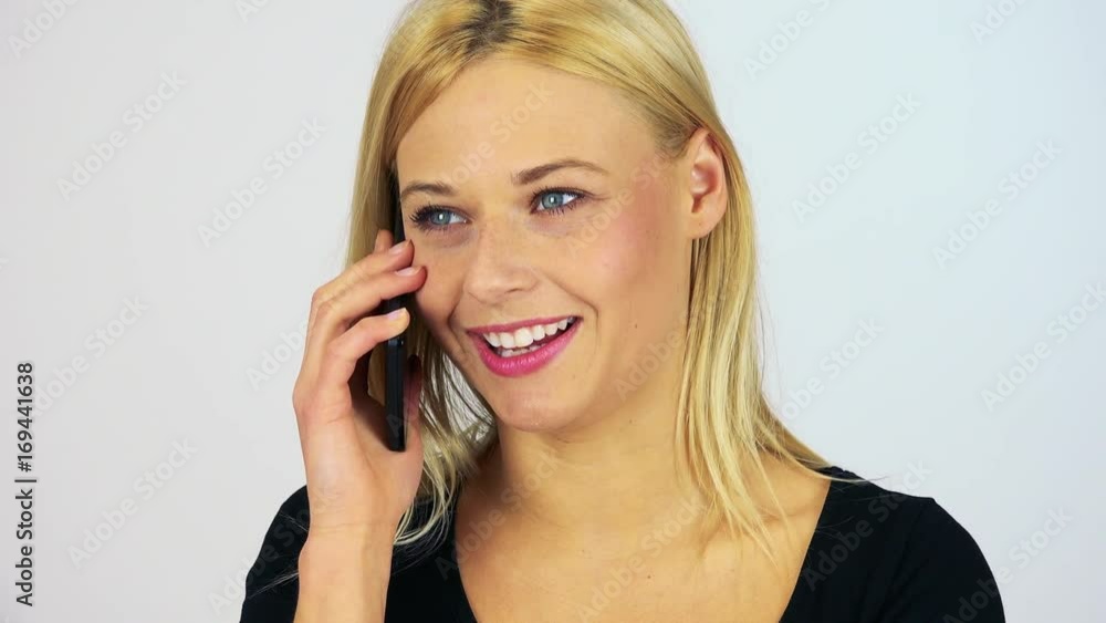A young attractive woman talks on a smartphone with a smile - closeup - white screen studio A young attractive woman talks on a smartphone with a smile - closeup - white screen studio