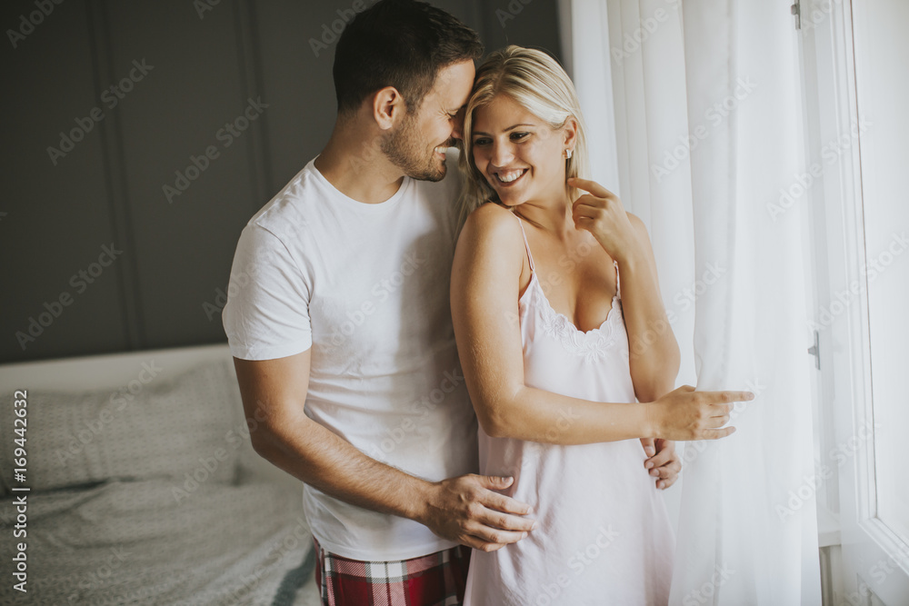 Lovely young couple standing by the window at morning Lovely young couple standing by the window at morning