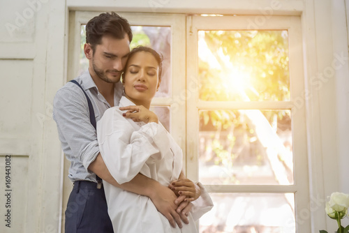 Couple standing by the window in the morning.