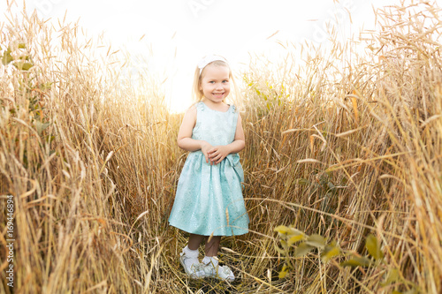 Little girl smiling on meadow at sunset