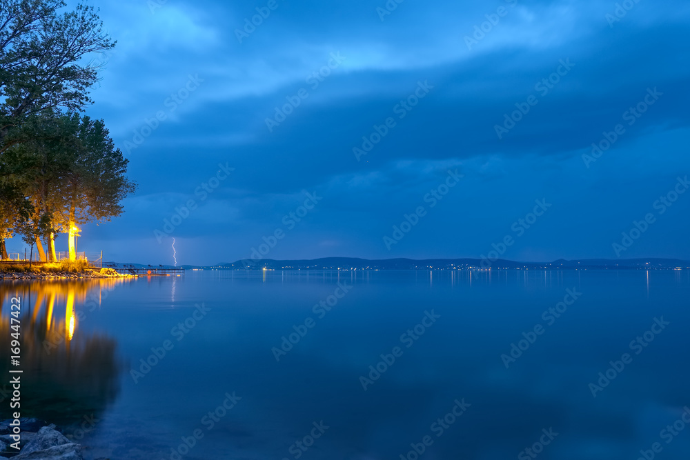 lightning bolts and storm clouds over Balaton lake in summer, in night, at low light