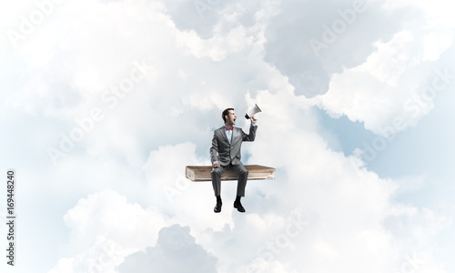 Businessman floating in blue sky and announcing something in loudspeaker