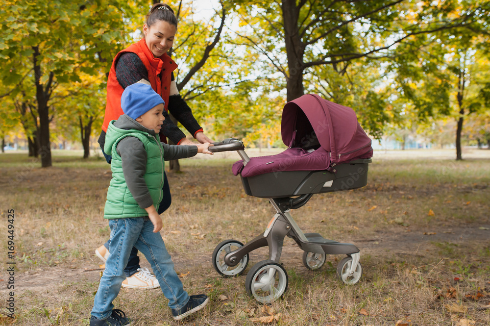 Mother walking with a baby pram in the park. Mother walking with a baby pram in the park.