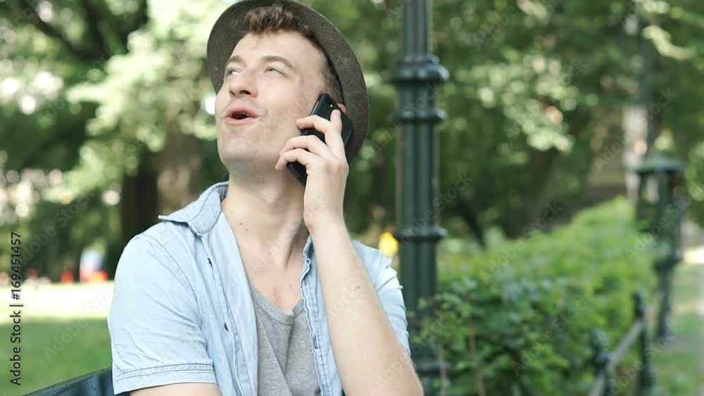 Young man relaxing in the park and chatting on cellphone with a friend, steadycam shot
Young man relaxing in the park and chatting on cellphone with a friend, steadycam shot