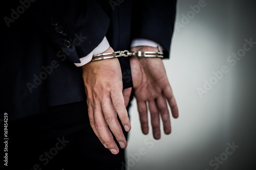 Businessman arrested with handcuffs on back for corruption and stealing millions of dollar euro money bank fraud and bribery. hands wide open