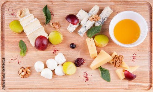 Cheese platter with fruit on a wooden board