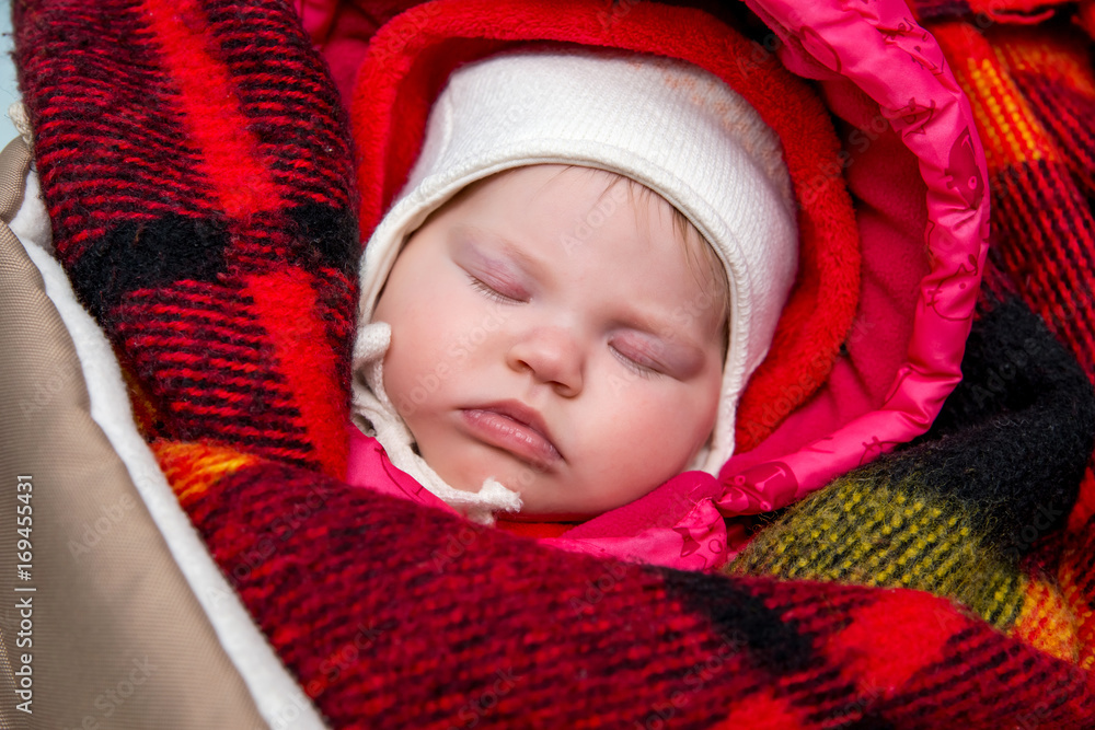 A sleeping baby in warm winter clothes and a blanket. A sleeping baby in warm winter clothes and a blanket.