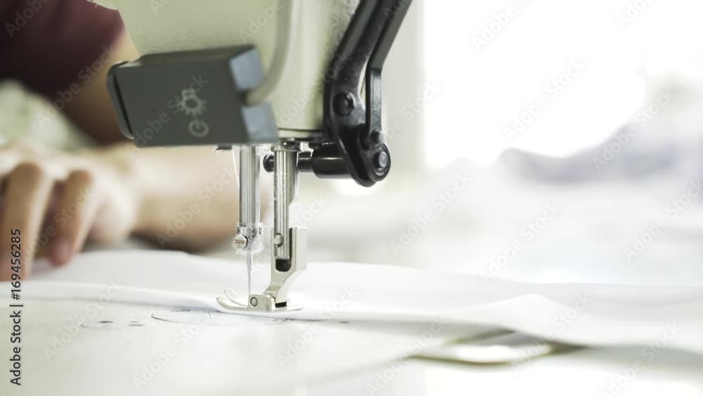 Close up of an unrecognizable semstress hands sewing a white shirt at a