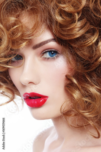 Fototapeta Naklejka Na Ścianę i Meble -  Young beautiful blue-eyed woman with curly hair and red lipstick