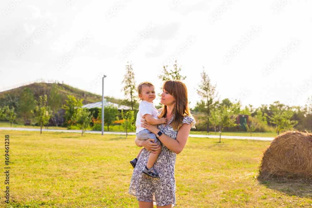 Cute cheerful child with mother play outdoors in park Cute cheerful child with mother play outdoors in park