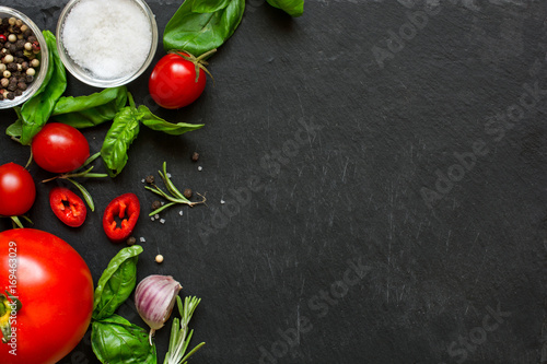 concept cook work with vegetables, spices and herbs on dark background.
