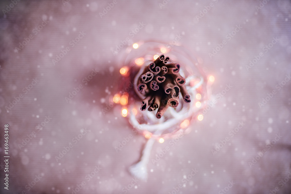 Obraz premium Top view to cinnamon sticks tightened together. Snow blur and Christmas bokeh lights background. Vintage Toned image.