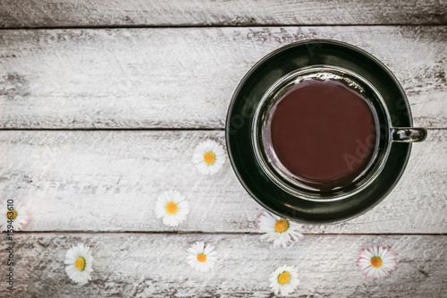 cup of coffee and Chamomile flowers on wooden background. cover, card. copy space.