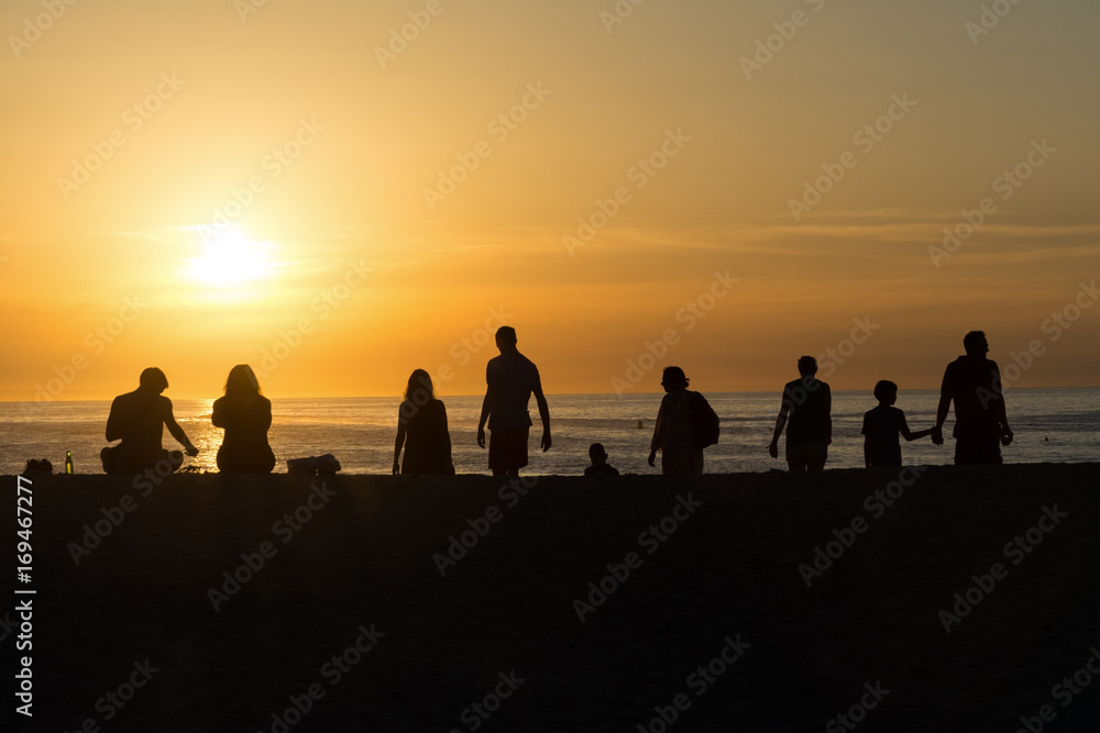 Silhouettes of people on the beach, watching the sunset Silhouettes of people on the beach, watching the sunset