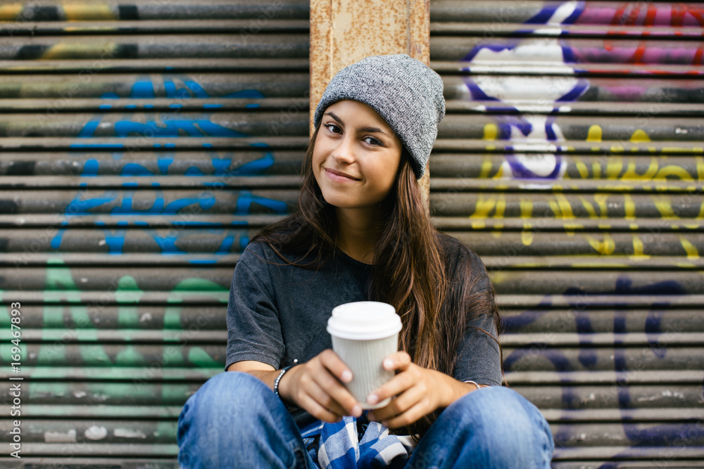 Portrait of a smiling skater girl holding a coffee sitting on her longboard. Portrait of a smiling skater girl holding a coffee sitting on her longboard.