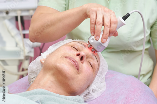 Hand with rf skin tightening device. Adult woman at the cosmetician. Modern technologies in cosmetology.