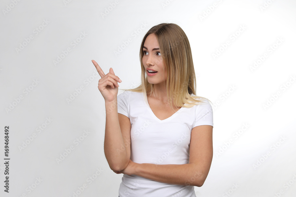 Hübsche blonde Frau erstaunt zeigt mit Finger in eine Richtung Hübsche blonde Frau erstaunt zeigt mit Finger in eine Richtung