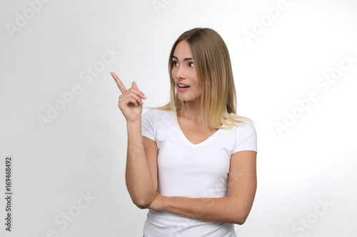 Hübsche blonde Frau erstaunt zeigt mit Finger in eine Richtung