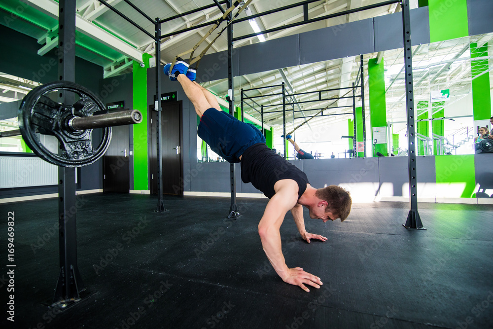 Athlete walking on his hands standing upside down in gym. Man doing push ups on his hands. Workout lifestyle concept. Full body length portrait