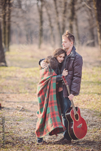 couple walking in a romantic mood with guitar outdoors in a park.