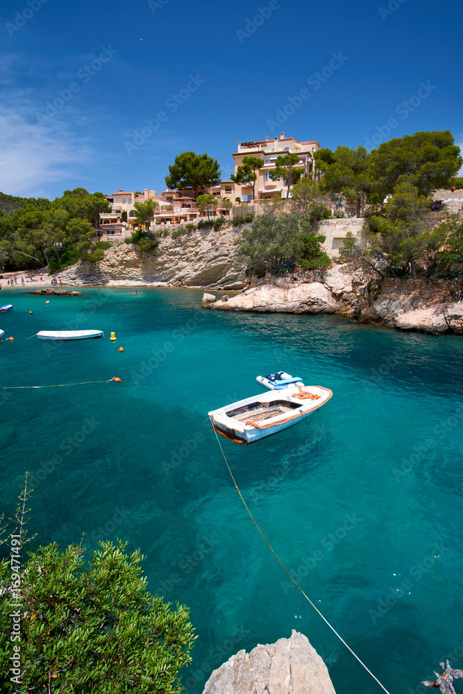 Sea bay a beautiful summer day blue clear water and granite stones. Boats above coral reef. Spain.