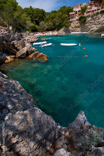 Sea bay a beautiful summer day blue clear water and granite stones. Boats above coral reef. Spain.