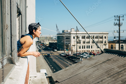 Girl looking outside with half body out of window.