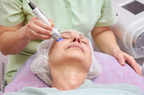 Adult female, rf skin tightening. Mature woman in cosmetology clinic.