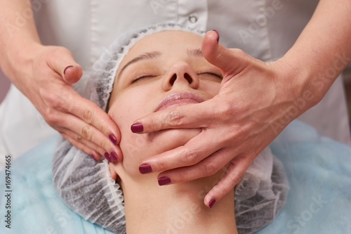 Hands massaging face close up. Cosmetic facial massage.