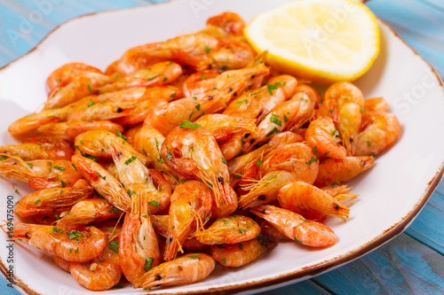 Shrimps with lemon and parsley on white plate