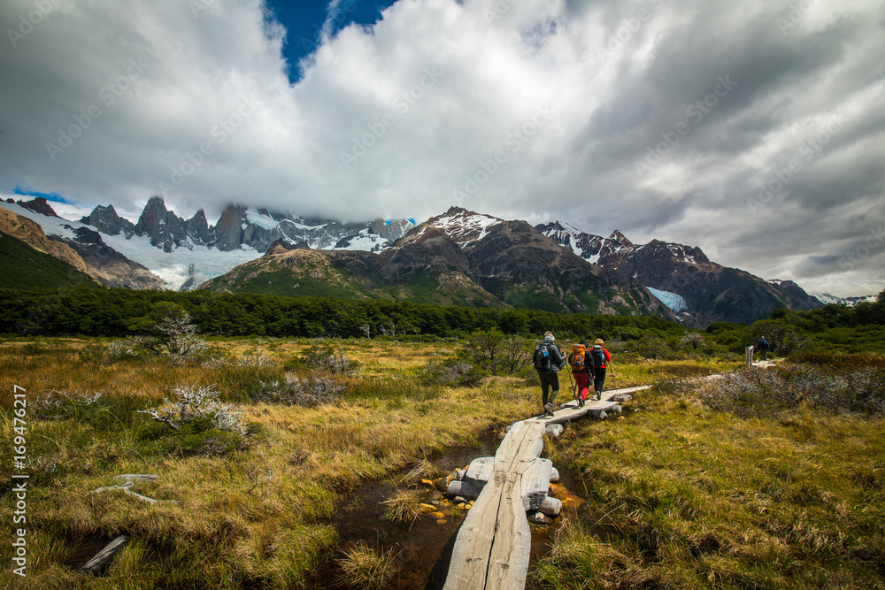 Naklejka premium Tourists are walking along a wooden bridge over a swamp. Shevelev.