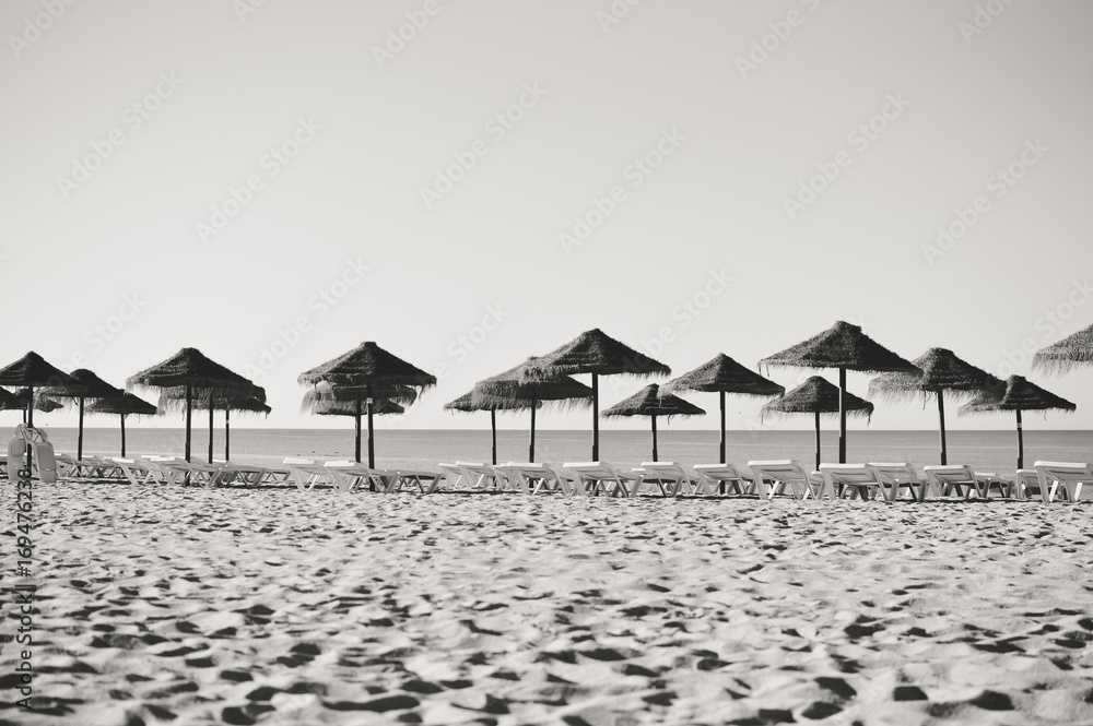 Sunny sky and chairs with parasol on the beautiful beach of Portugal